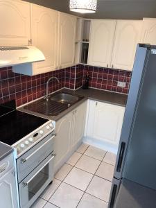 a kitchen with white cabinets and a sink at St Andrews Bungalow in Fife