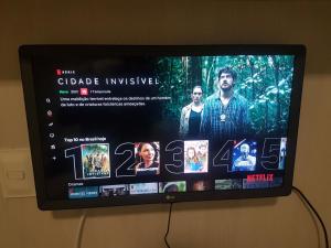 een flatscreen-tv die aan de muur hangt bij quarto social privado ap compartilhado in Capão da Canoa