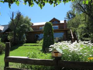 a house with a yard with flowers and a bird house at Cabaña Paseo del Sol in San Martín de los Andes