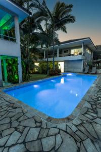 a large blue swimming pool in front of a house at Pousada Palmeira Real in Itaguaí