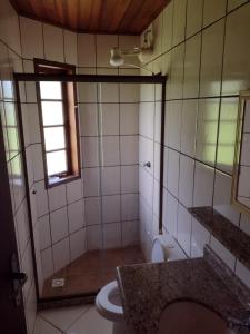 uma casa de banho com um chuveiro, um WC e uma janela. em Casa Paraty em Paraty