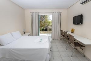 a bedroom with a bed and a desk and a television at Pousada Palmeira Real in Itaguaí