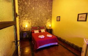 a bedroom with a red bed in a stone wall at Posada de campo Maia in Merlo