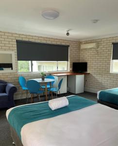 a bedroom with a bed, chair and a television at Beach Park Motel in Wollongong