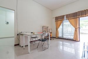 a white room with a table and chairs and a window at The Lima Guest House Syariah Mitra RedDoorz in Cirebon