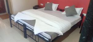 a bedroom with a large bed with white sheets and pillows at Hotel Rajendra in Chinchani
