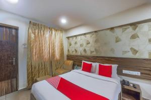 een hotelkamer met een groot bed met rode kussens bij Serenity Inn in Chennai