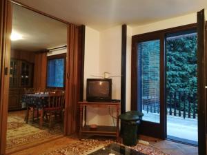 a living room with a tv and a table and a window at GREEN GARDEN in Zlatibor