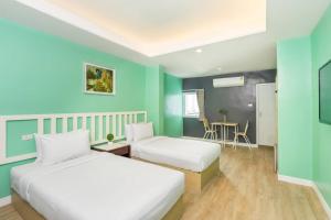 two beds in a room with blue and green walls at Ratchada Point Hotel in Bangkok