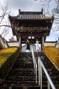 dos mujeres subiendo las escaleras delante de un edificio en Temple Hotel 正暦寺, en Ayabe