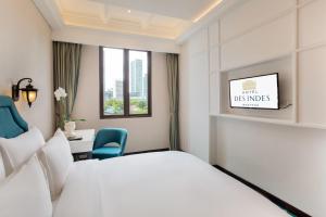 a hotel room with a bed and a desk and a window at Hotel Des Indes Menteng in Jakarta