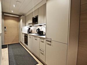 uma cozinha com armários brancos e um lavatório num quarto em Levillas Levin Kunkku em Levi