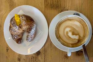 un piatto con un prodotto da forno e una tazza di caffè di VillaTullia Ferienhaus mit Seesicht Gardasee a Tignale