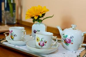 un vassoio con tre tazze da tè e un vaso con un fiore giallo di Villa Cagnola a Varese