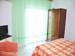 a bedroom with a bed and a chair and a window at Apartments Lovran in Lovran