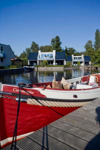 een rode en witte boot is aangemeerd bij een dok bij Amsterdam / Loosdrecht Rien van den Broeke Village in Loosdrecht