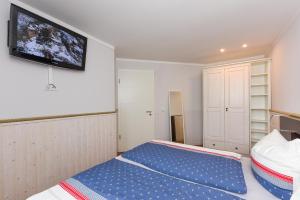 ein kleines Schlafzimmer mit einem Bett und einem Flachbild-TV in der Unterkunft Ferienwohnungen MARENOR in Bensersiel