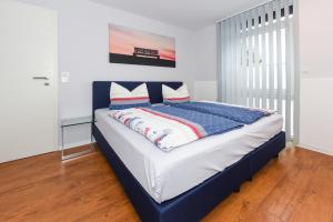 Bett mit blauem Kopfteil in einem Zimmer in der Unterkunft Ferienwohnungen MARENOR in Bensersiel