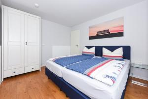 una camera con letto e armadietto bianco di Ferienwohnungen MARENOR a Bensersiel