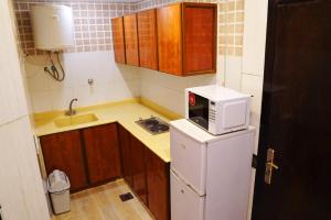a small kitchen with a microwave on top of a refrigerator at لـــــــؤلــــــؤة البـــــــحر Loaloat Al-Bahar in Al Khobar