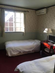 a room with two beds and a desk and a window at Chateau Lausanne in Hakuba