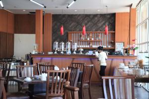 a woman standing at the bar of a restaurant at Aerotel Smile Losari in Makassar