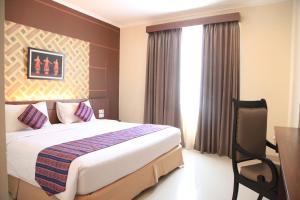 a hotel room with a bed and a desk and a window at Aerotel Smile Losari in Makassar