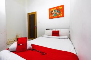 a bedroom with two beds with red pillows at RedDoorz @ Hertasning Area 2 in Makassar