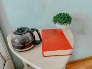 a table with a tea kettle and two books on it at Комфорт-апартаменты Chilpil - центр - быстрое бесконтактное заселение 24х7 in Brest