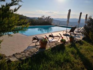 una piscina con 2 sillas de césped y una piscina en Casa del Tramonto, en Civitella in Val di Chiana