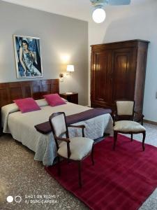 een slaapkamer met een groot bed en 2 stoelen bij VILLA ANTONIETTA in Cesenatico