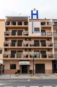an apartment building with a blue sign on it at Hotel Herasu in Peniscola