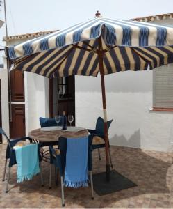 a table and chairs under an umbrella on a patio at El Rincón de Bolonia in Bolonia