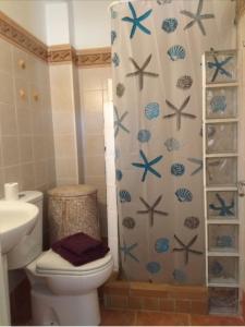 a bathroom with a toilet and a shower curtain at El Rincón de Bolonia in Bolonia