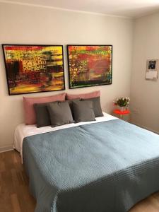 a bedroom with a blue bed with three paintings on the wall at Stemningsfuld lejlighed - 3 minutters gang fra H.C. Andersens Hus in Odense