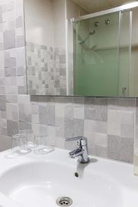 a bathroom sink with a faucet and a mirror at Hotel Herasu in Peniscola