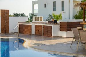 a swimming pool with a kitchen next to a house at Seafront Protaras Villas in Protaras