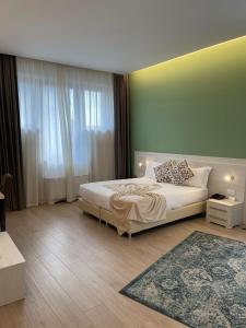 1 dormitorio con cama blanca y pared verde en Palazzo Marignano Hotel en Melegnano