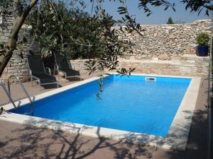 una piscina azul con 2 sillas y una pared de piedra en Apartments Percan 447 en Krnica