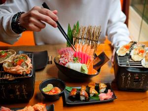 a person is eating food on a table with sushi at Swissotel Bangkok Ratchada in Bangkok