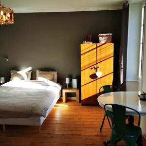 a bedroom with a bed and a table and a dresser at Le Bonheur- Suite Cognac in Hiersac