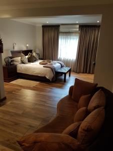 Cornerstone Guest Lodge في بريتوريا: غرفة نوم كبيرة مع سرير وأريكة