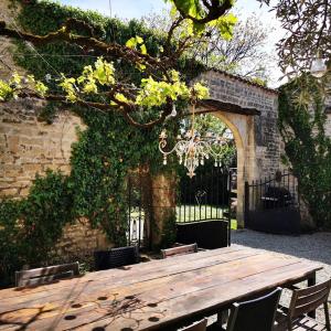 uma mesa de madeira num jardim com um arco em Le Bonheur- Suite Cognac em Hiersac