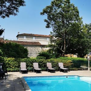 une piscine avec des chaises longues et un bâtiment dans l'établissement Le Bonheur- Suite Cognac, à Hiersac