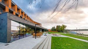 un edificio con puertas de cristal y un patio con mesas. en Notera Hotel SPA en Charzykowy