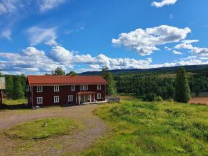a red house on a hill with a green field at Backamgården in Sälen