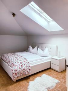 1 dormitorio con 1 cama blanca grande y tragaluz en Ferienwohnung Karasek mit Seeblick, en Sattendorf