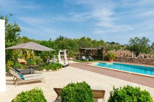 a swimming pool with chairs and an umbrella next to a resort at Villa Sa Cuina in Sant Rafael de Sa Creu