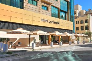 a hotel with tables and umbrellas in front of a building at Hotel Lac Leman, LES BERGES DU LAC in Tunis