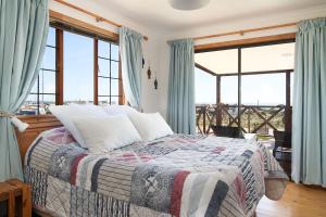 Schlafzimmer mit einem Bett und großen Fenstern in der Unterkunft Dogstone Cottage in Hondeklipbaai